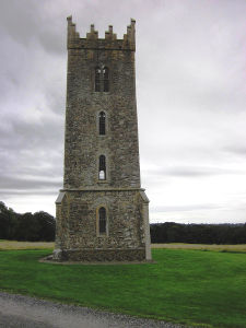 A four storied tower in grey stone, with narrow, arched windows.